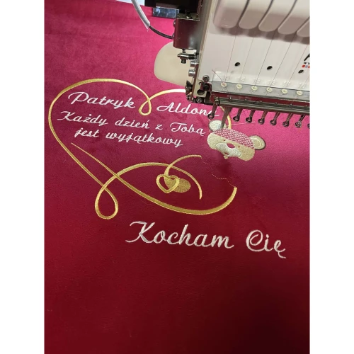 Haftowanie czerwonej poduszki z imionami Patryk i Aldona oraz dedykacją Kocham Cię